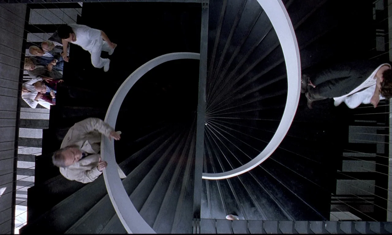 Dellamorte Dellamore (1994) movie still: wide — A modern geometric spiral staircase features stark black treads and a curving white handrail.…