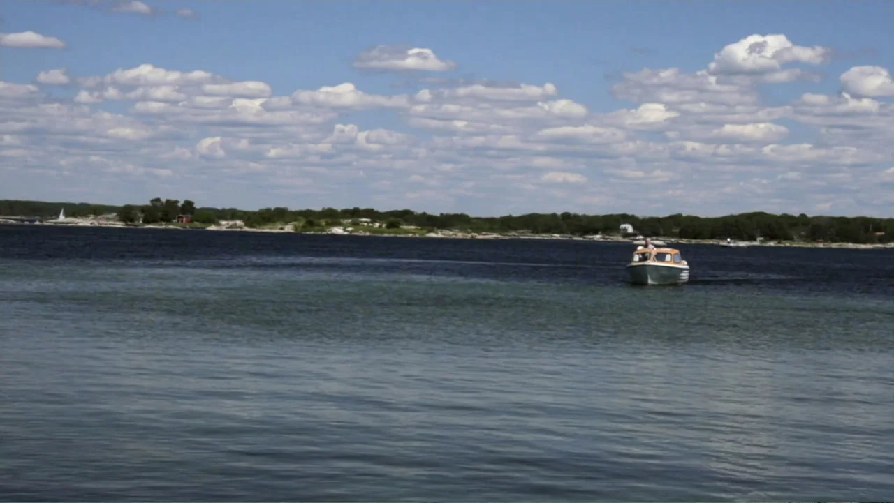 When Strangers Click: Five Stories from the Internet (2011) movie still: wide — A small motorboat moves across a vast, calm sea under a bright,…