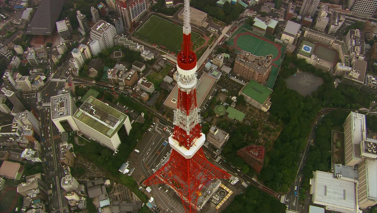 Cutie Honey (2004) movie still: establishing — An aerial view shows a red and white communication tower rising above Tokyo buildings. Densely packed…