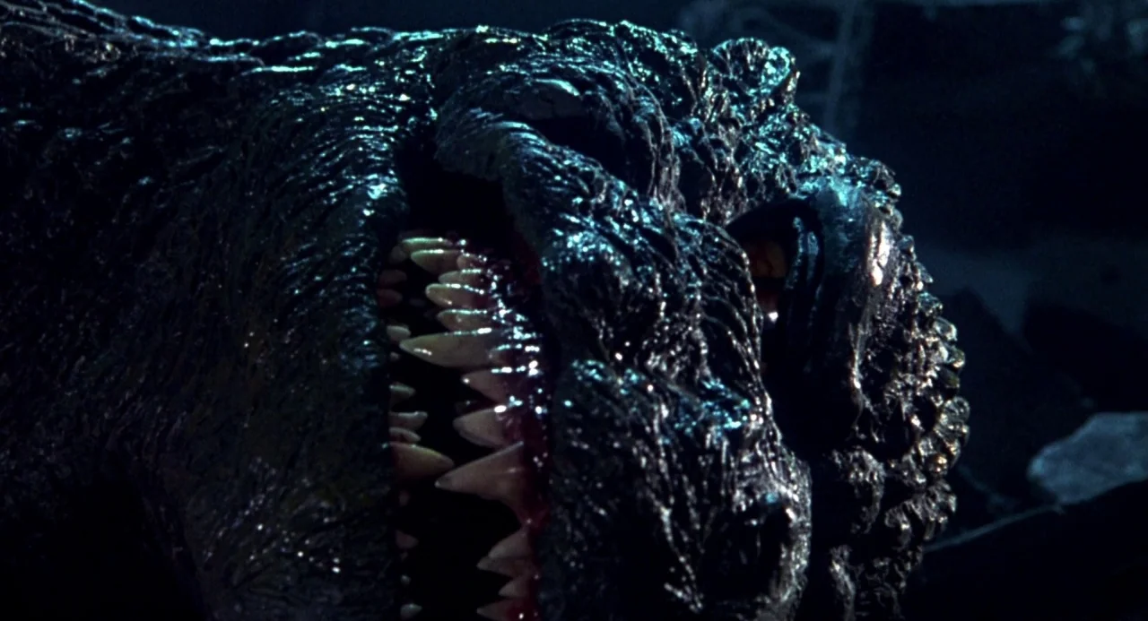 Godzilla vs. Destoroyah (1995) movie still: closeup — A dark environment filled with debris and rubble from a ruined urban area. A massive reptilian…