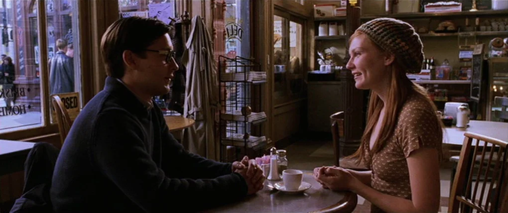 Spider-Man 2 (2004) movie still: medium — A quiet diner interior with wooden furniture and large glass windows facing a street. A young man and…
