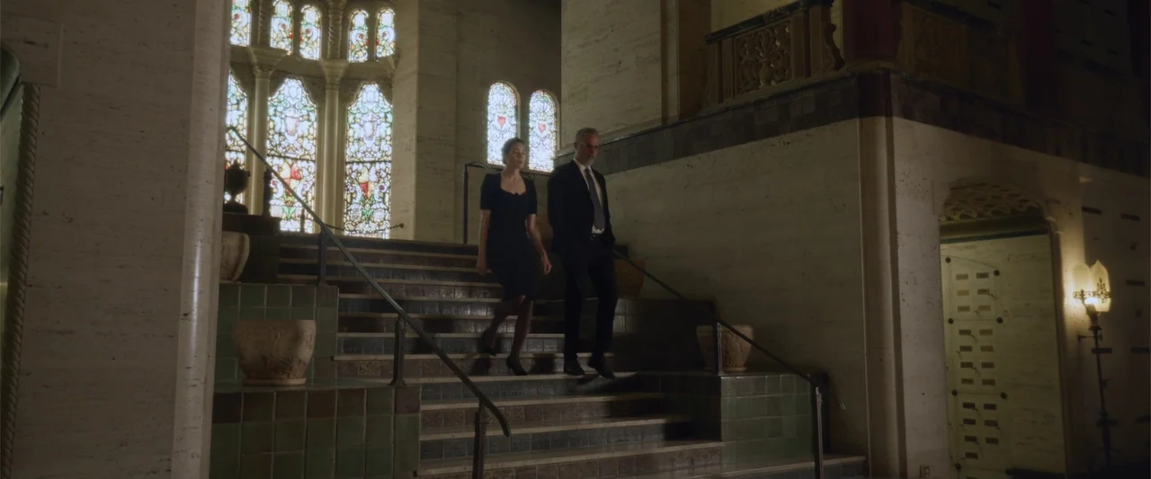Black Site (2022) movie still: fullbody — A stone mausoleum with high ceilings features a grand central staircase and stained glass. A woman in a…