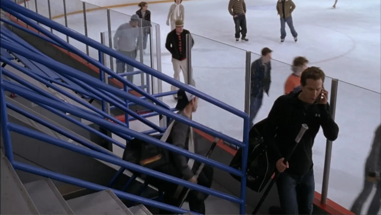 Just Friends (2005) movie still: medium — A man walks up stadium stairs carrying a hockey bag near a glass partition. In the background several…