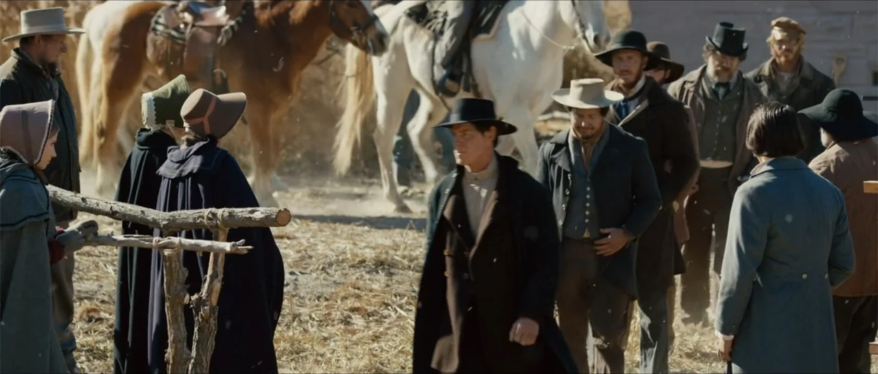 Out of Liberty (2019) movie still: fullbody — A dusty outdoor yard features a rough wooden fence and horses in the background. Several men and women…