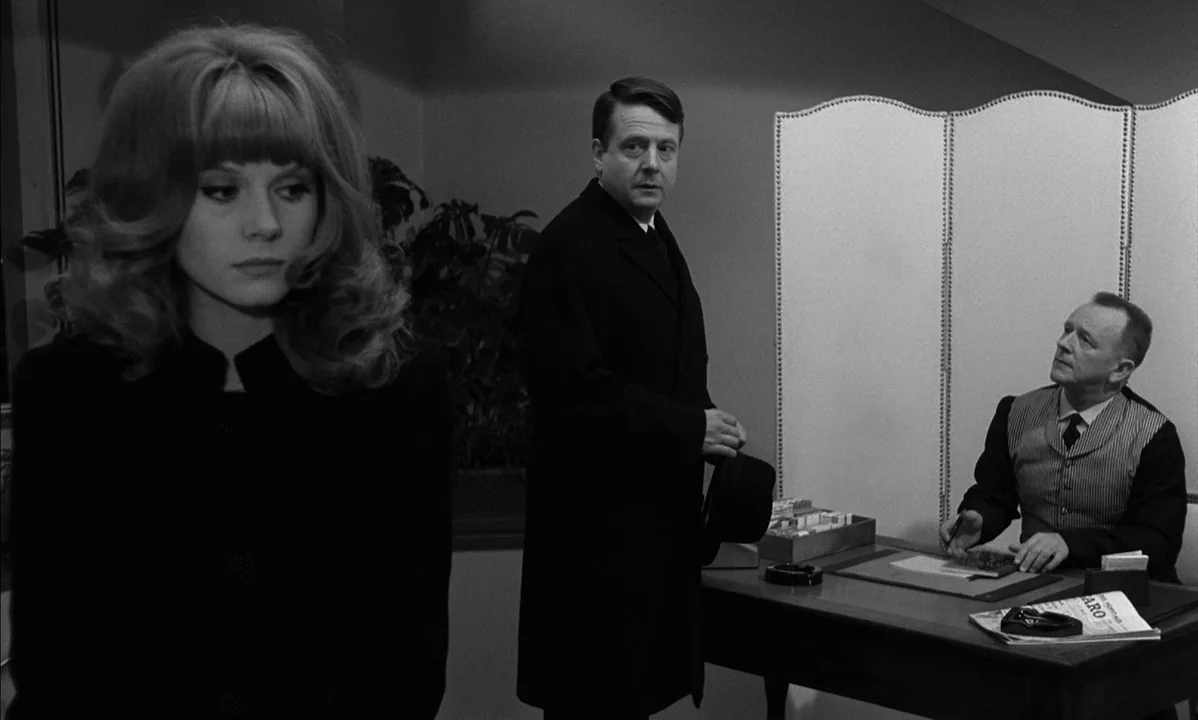 La Peau Douce (The Soft Skin) (1964) movie still: medium — A 1960s room featuring a desk with a white privacy screen behind it. A woman in the…