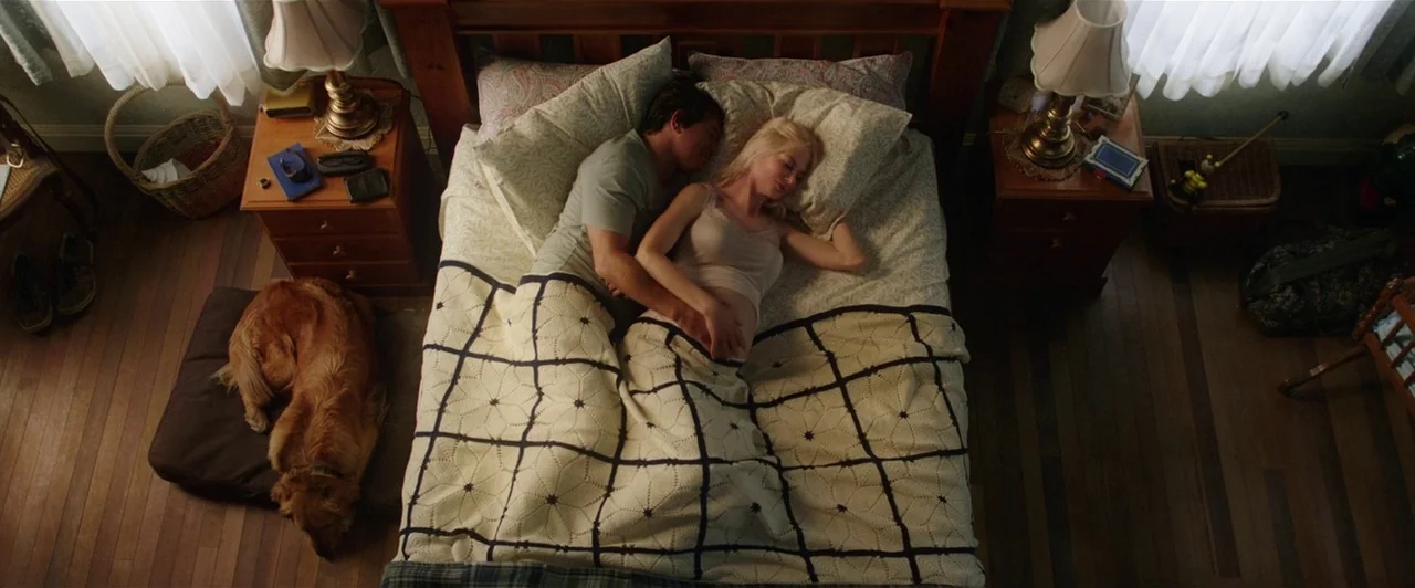 Aquaman (2018) movie still: wide — A well-lit bedroom features a queen-sized wooden bed with a patterned crochet blanket cover. A couple sleeps in…