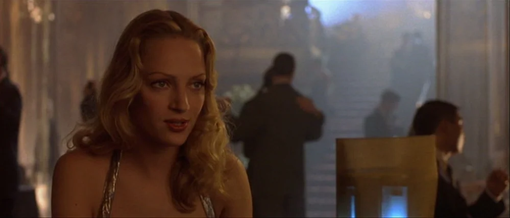 Gattaca (1997) movie still: medium — A spacious ballroom filled with blurred silhouettes of people dancing near a staircase. The woman is in the…