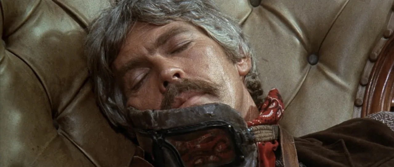 Duck, You Sucker (1971) movie still: closeup — A person rests head against a tufted tan leather armchair cushion. The man with a mustache has his…