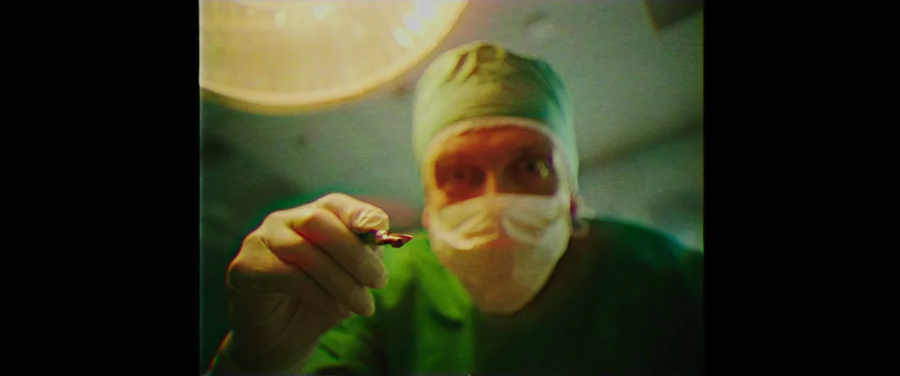 Mindhorn (2016) movie still: closeup — A sterile medical environment is viewed from the perspective of an unconscious patient. A surgeon in scrubs…