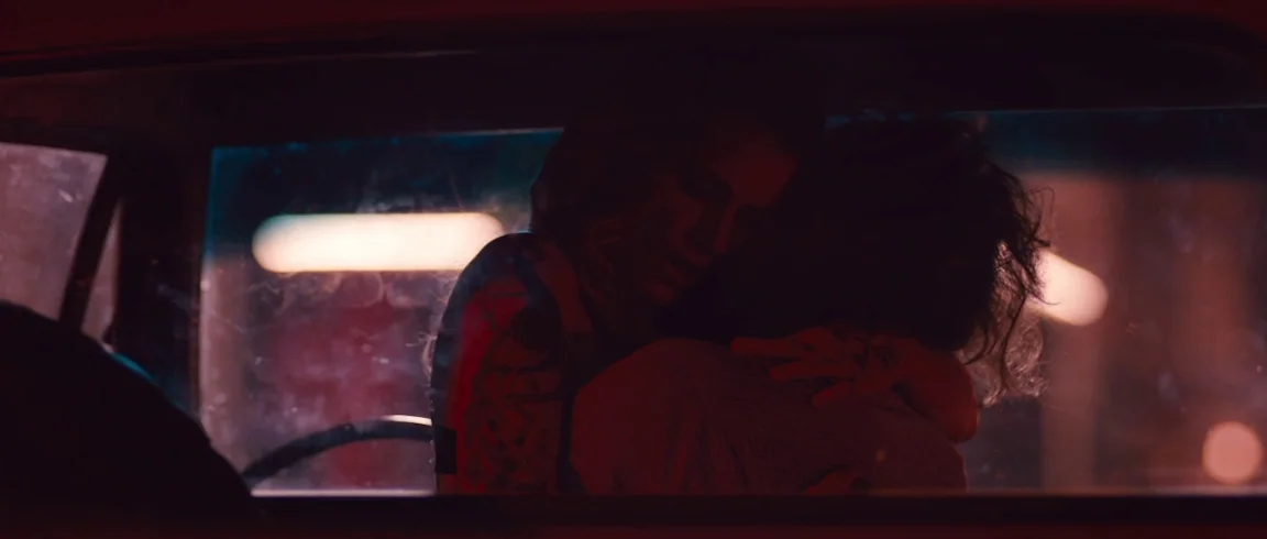 Broken Circle Breakdown (2012) movie still: medium — A close-up view of two people embracing inside a car at night. Red neon light glows through the…
