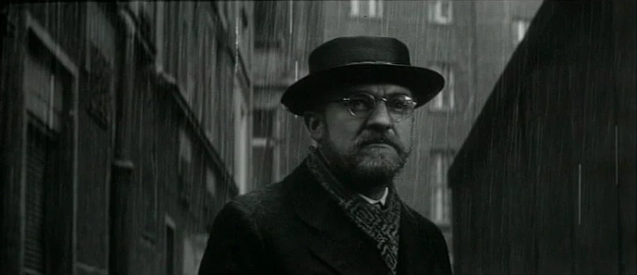And The Fifth Horseman is Fear (1965) movie still: medium — A rain-drenched urban alleyway is flanked by dark stone buildings with rectangular…
