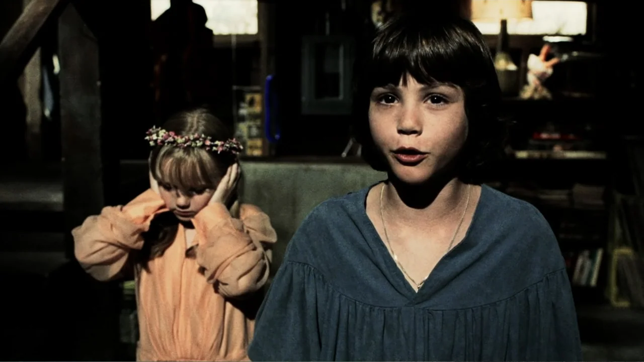 The Butterfly Effect (2004) movie still: medium — A dark, cluttered basement interior features wooden stairs and dim background details. A child…