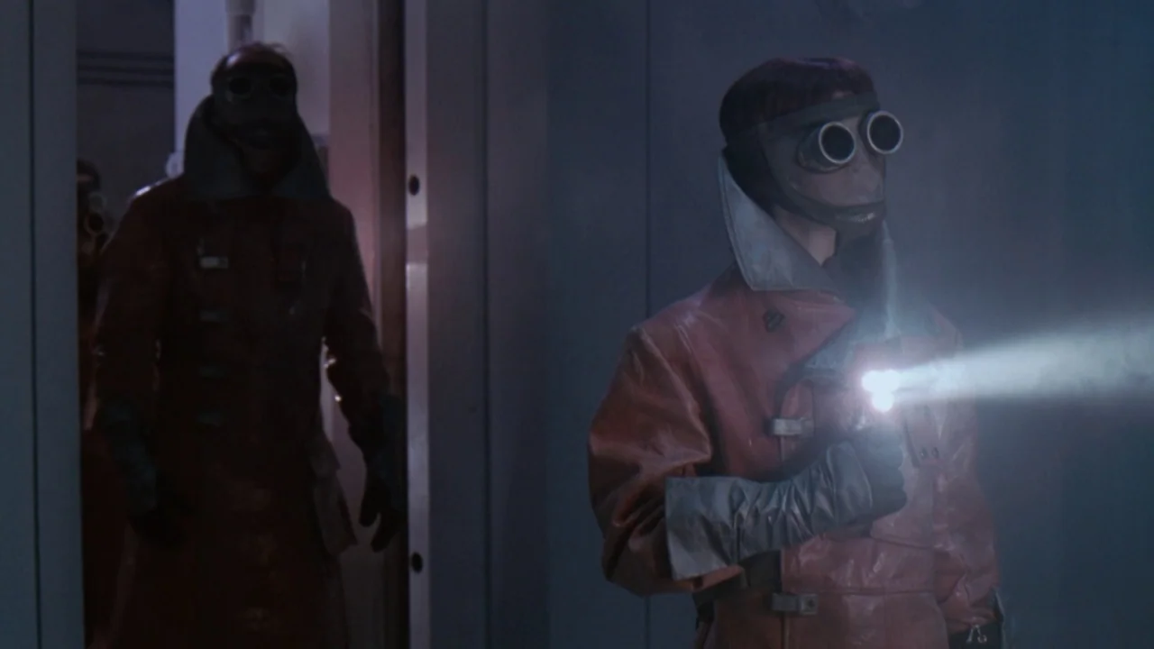 Jason X (2001) movie still: medium — A dimly lit industrial hallway features smooth walls and a sterile, minimalist aesthetic. Two figures in…
