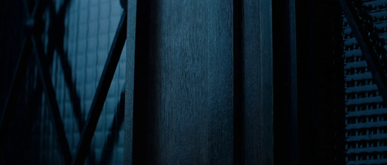 Outside Satan (2011) movie still: closeup — A close-up of dark stained wooden window frame slats against a glass pane. The wood grain is visible…