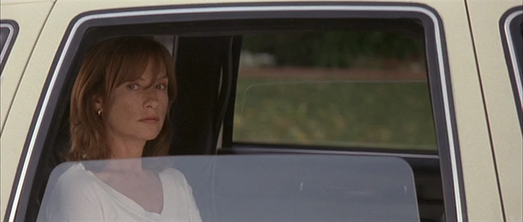 I Heart Huckabees (2004) movie still: medium — A woman sits in the passenger seat of a light-colored vehicle during the day. The window frame of the…