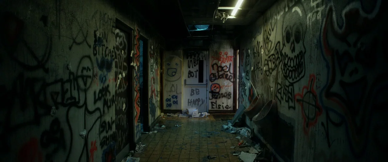 The Canal (2014) movie still: establishing — A dark, dilapidated public restroom features walls covered in extensive multicolored graffiti and…