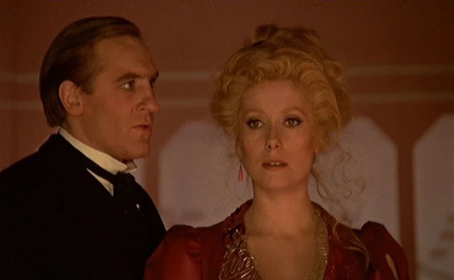 The Last Metro (1980) movie still: medium — A well-lit room with soft pinkish walls provides the backdrop for a formal event. A man in a dark suit…