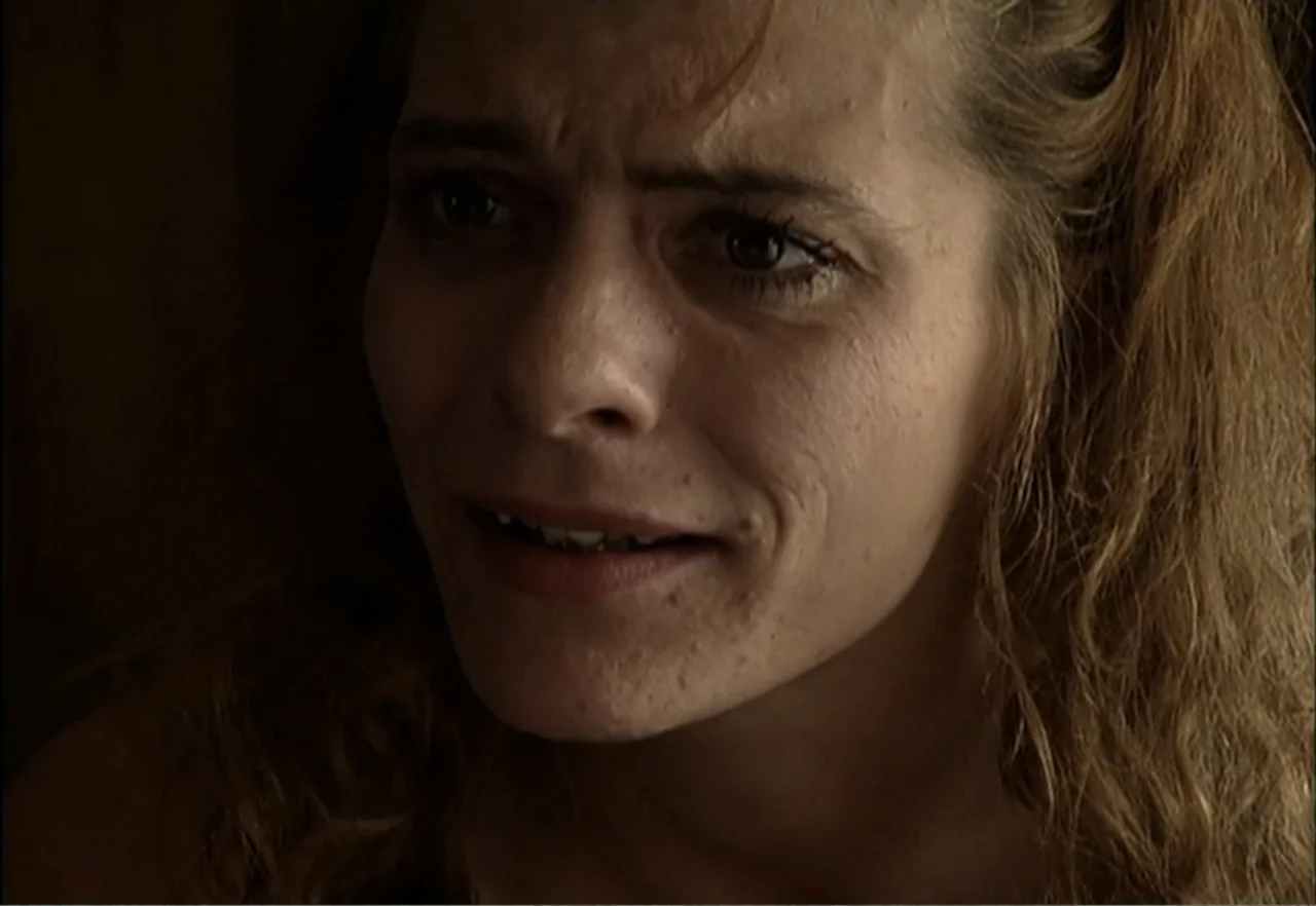 Broken Child (2000) movie still: closeup — An interior space with dim, low-key lighting and a dark, indistinct background. A woman in her thirties…