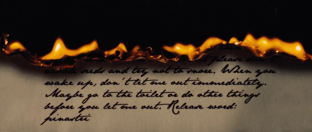 The Duke of Burgundy (2014) movie still: closeup — A piece of aged paper with cursive writing is being destroyed by a moving flame. The top edge of…