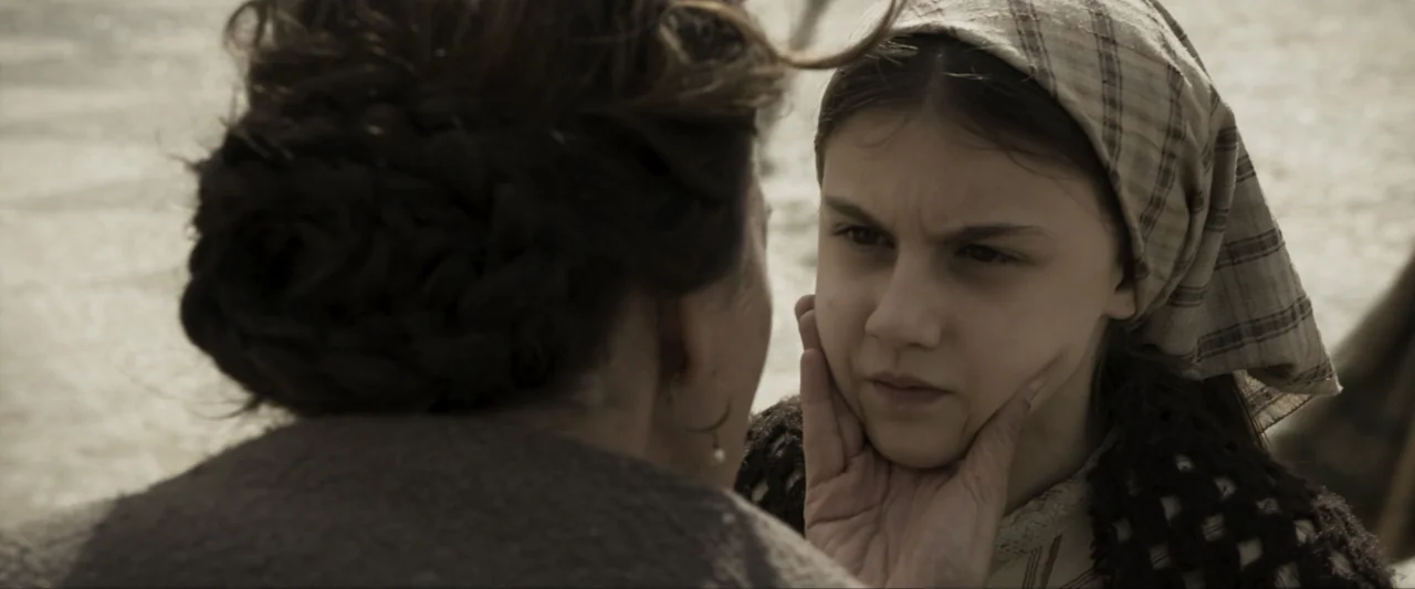 Fatima (2020) movie still: closeup — Two individuals stand close together in an outdoor area during the daylight. A woman uses her hand to cradle…