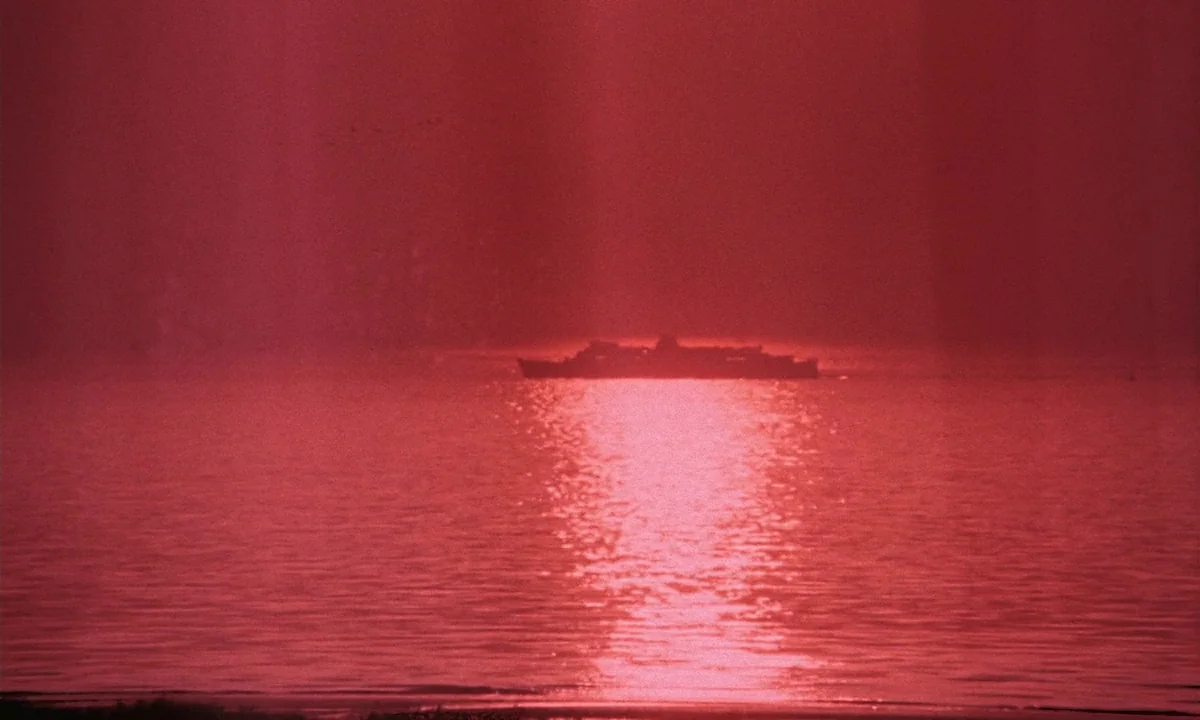 Daughters of Darkness (1971) movie still: wide — A vast expanse of water is tinted in intense shades of red and darkness. A silhouette of a ship…