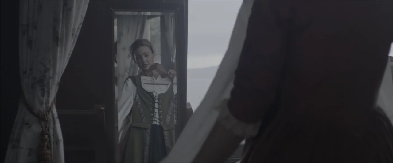 Cinderella's Curse (2024) movie still: medium — An interior bedroom with floral curtains and a tall standing mirror reflecting a woman. A woman in a…