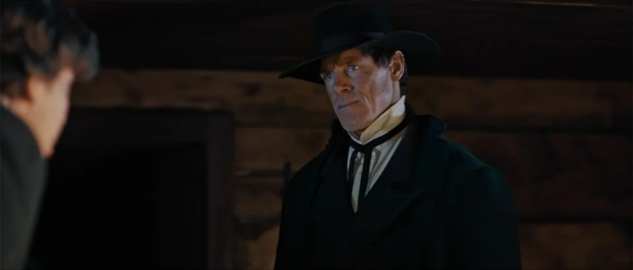 Out of Liberty (2019) movie still: medium — A dark, wood-paneled interior space reflects a mid-19th-century domestic setting. A man in a black coat…