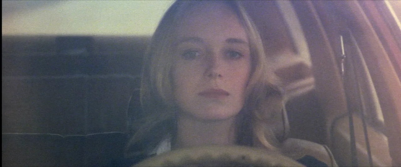 The Beyond (1981) movie still: closeup — A close-up view shows a woman sitting behind the steering wheel of a vehicle. Light filters through the…