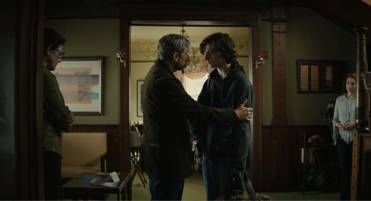 Beautiful Boy (2011) movie still: medium — A house interior features beige walls, dark wood trim, and a framed abstract print. An older man stands…