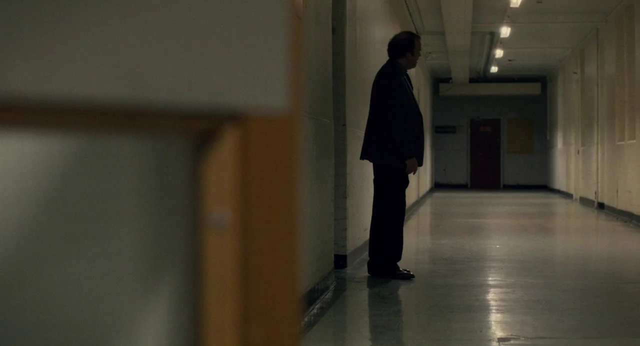 Berberian Sound Studio (2012) movie still: fullbody — A long, sterile corridor with light beige walls and a reflective tiled floor. A man stands…