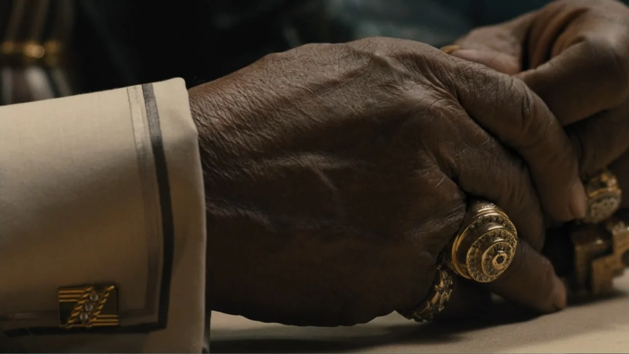 Bleed for This (2016) movie still: closeup — A close-up view of two mature hands resting clasped on a flat surface. The person wears a cream-colored…