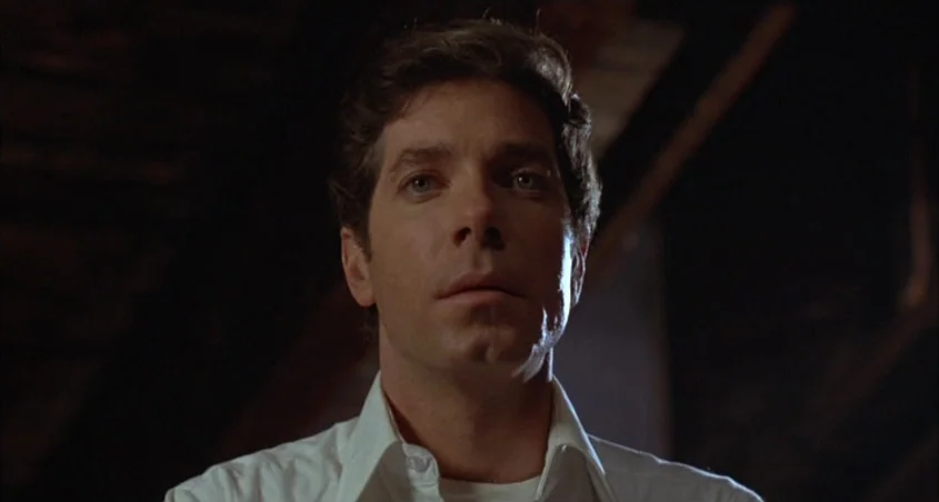 Scanners (1981) movie still: closeup — A man stands in a dark environment with indistinct shadows behind him. He faces the camera directly while…