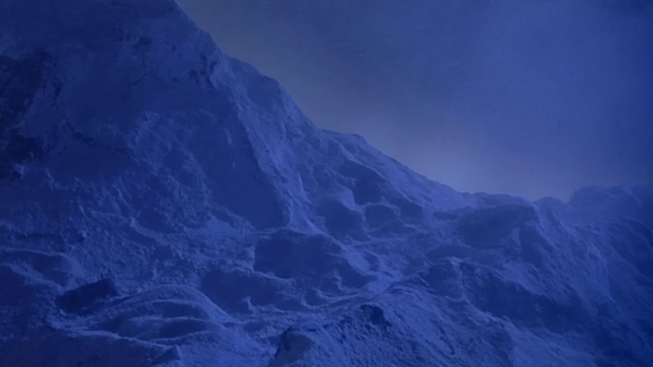 The Bride with White Hair II (1993) movie still: establishing — A desolate mountain range is covered in deep, textured snow under darkness. No…
