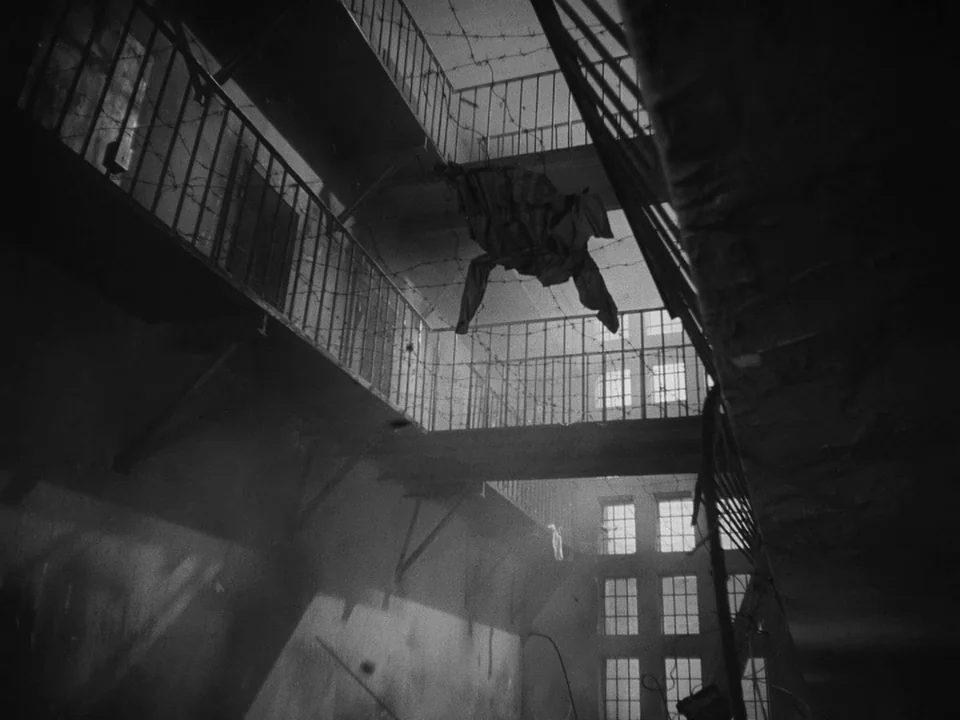 Ivan’s Childhood (1962) movie still: establishing — A dark, multi-level structure features iron railings and barbed wire strung between tiers. A…