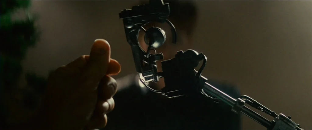 Blade Runner (1982) movie still: closeup — A dark indoor space contains a detailed mechanical object held in the foreground. The prosthetic device…