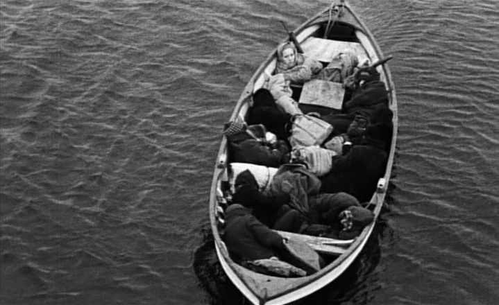 The Passion of Anna (1969) movie still: wide — A wooden rowboat sits in dark rippling water filled with several bundled-up individuals. The…