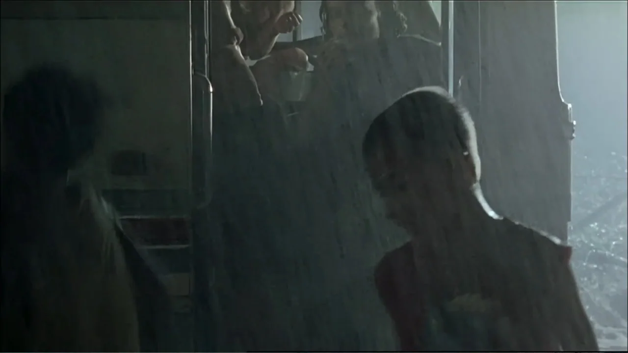 In the Middle of the World (1990) movie still: medium — A dark, rainy outdoor area at night with a bus waiting in the background. A young boy stands…