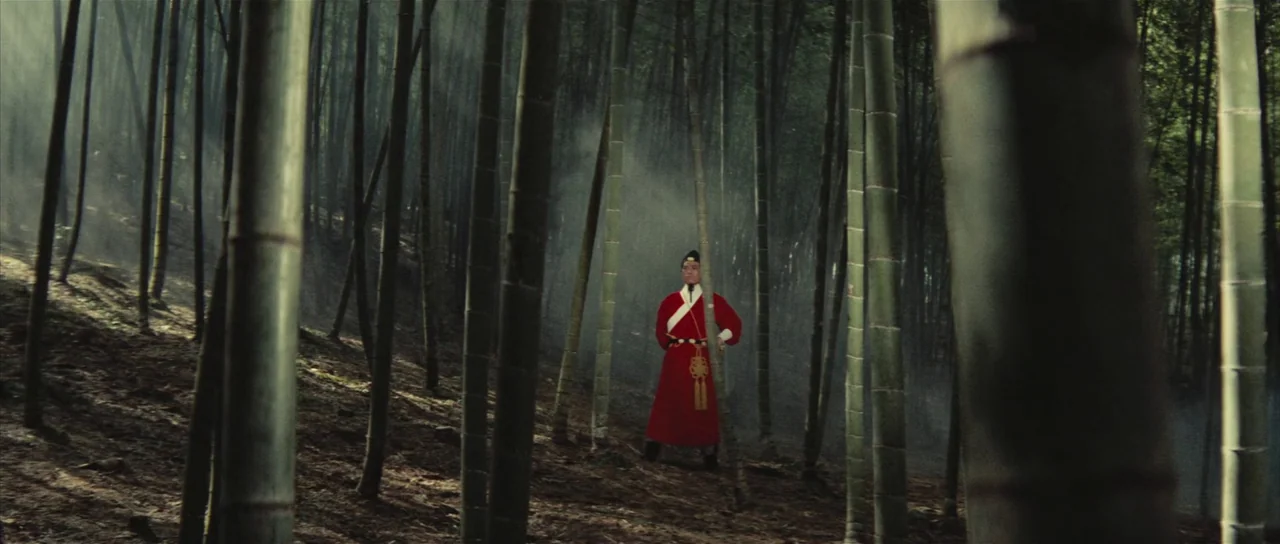 A Touch of Zen (1971) movie still: wide — A dense bamboo grove with thin stalks and light mist filtering through the trees. A lone man in a bright…