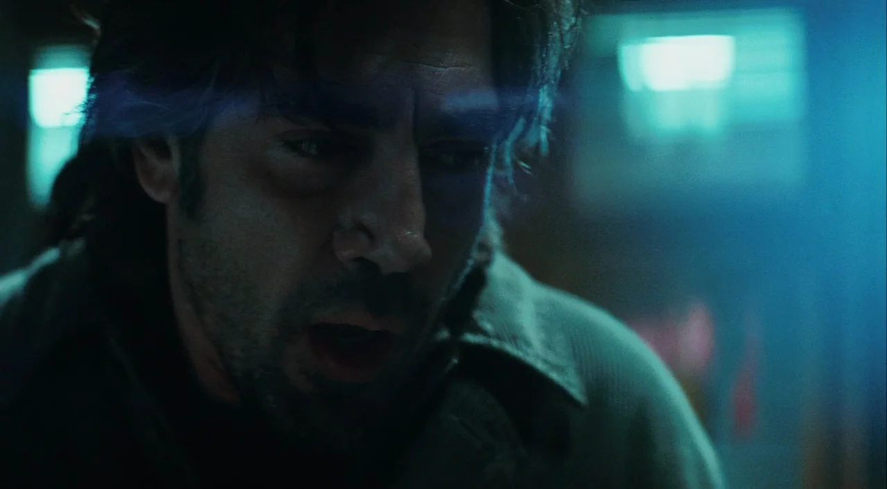 Biutiful (2010) movie still: closeup — A dimly lit interior space filled with cool-toned blue ambient light and shadows. A man with dark messy hair…