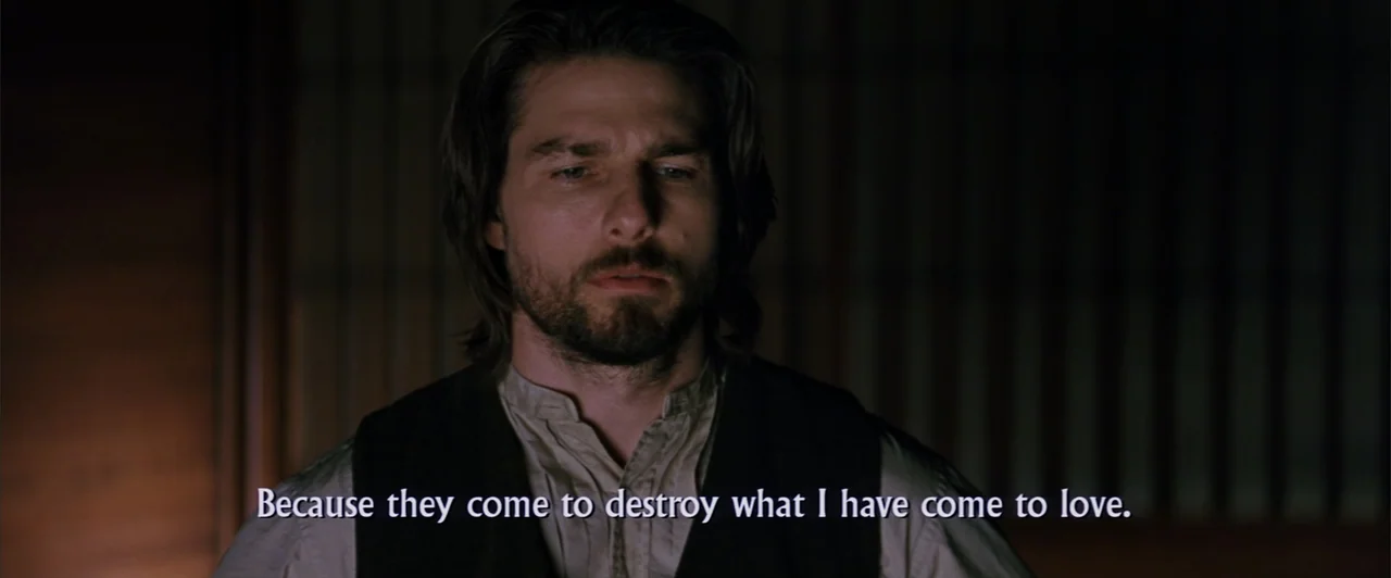 The Last Samurai (2003) movie still: closeup — A dim, traditional interior with shoji screen detailing in the dark background. A man with a dark…