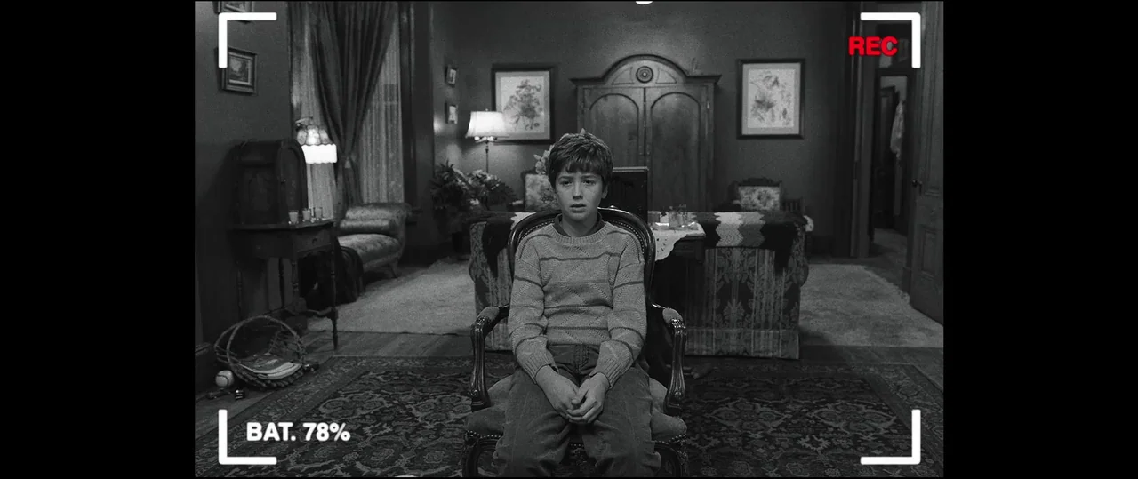 Insidious: Chapter 2 (2013) movie still: medium — A dark parlor filled with antique furniture, draped curtains, and framed wall art. A young boy…