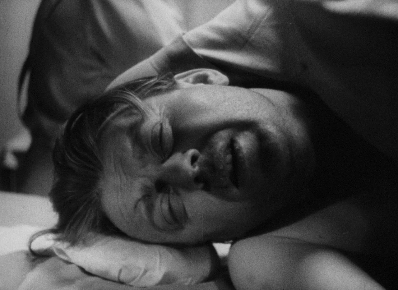 Krakatit (1948) movie still: closeup — A man lies on a pillow in a dimly lit clinical setting. His head rests sideways as his eyes remain closed.