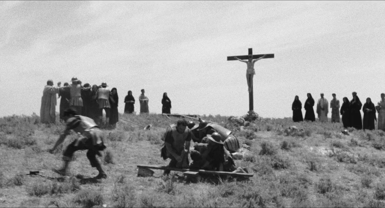 The Gospel According To St. Matthew (1964) movie still: wide — A desolate hilltop covered in dry, sparse vegetation under a bright, cloudless sky.…