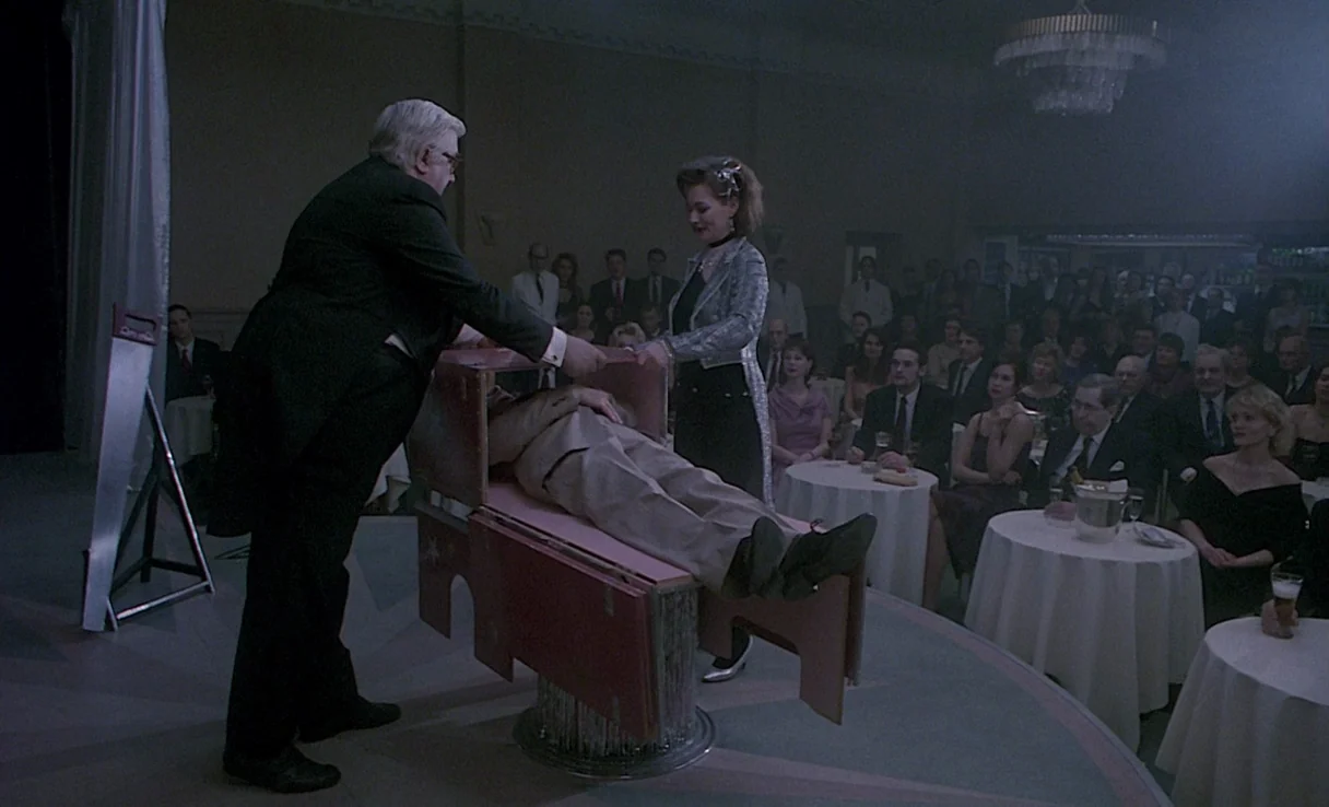 Songs from the Second Floor (2000) movie still: fullbody — A dimly lit ballroom with round tables and an audience watching a stage performance. A…