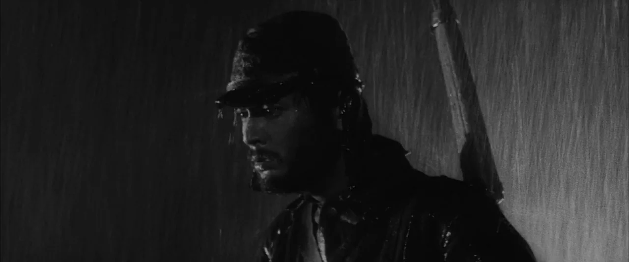 The Human Condition III: A Soldier’s Prayer (1961) movie still: closeup — A dark, rain-streaked exterior scene illuminated by high-contrast…