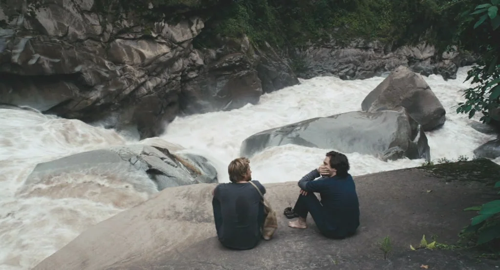 My Son, My Son, What Have Ye Done? (2009) movie still: wide — Two men sit on a flat rock outcrop overlooking a churning, muddy white-water river.…
