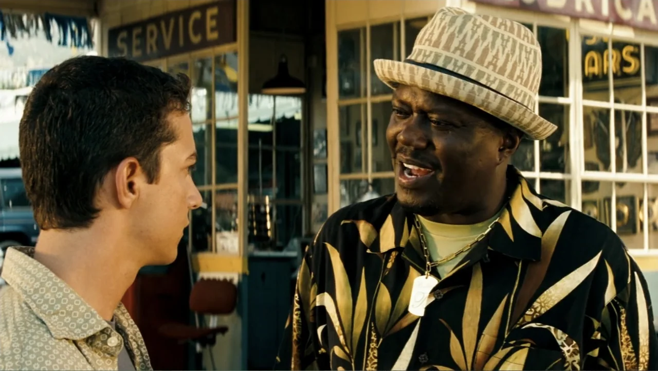 Transformers (2007) movie still: medium — A roadside gas station with glass service windows and vintage signage in the background. A man in a…