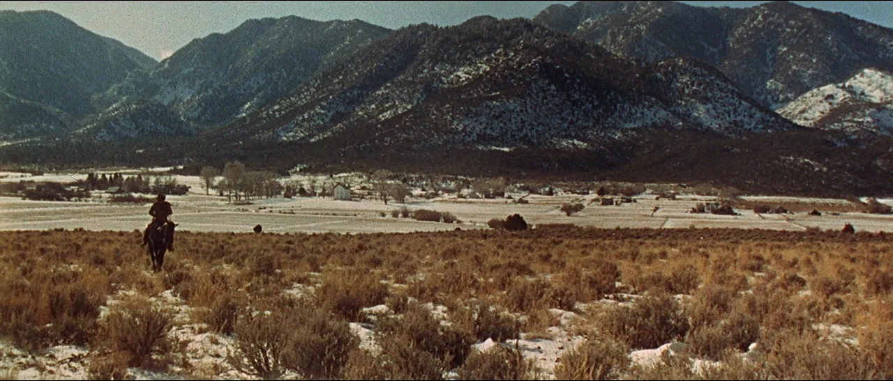 The Appaloosa (1966) movie still: wide — A vast, snow-sprinkled sagebrush valley sits beneath towering, dark mountain ranges. A single rider on…