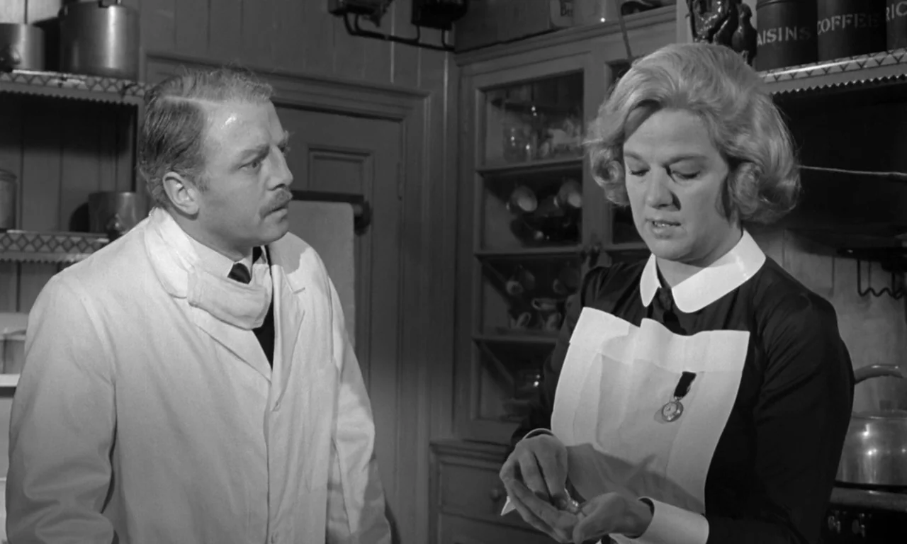 Seance on a Wet Afternoon (1964) movie still: medium — A traditional kitchen with wooden cabinetry and vintage storage tins on shelves. A nurse…