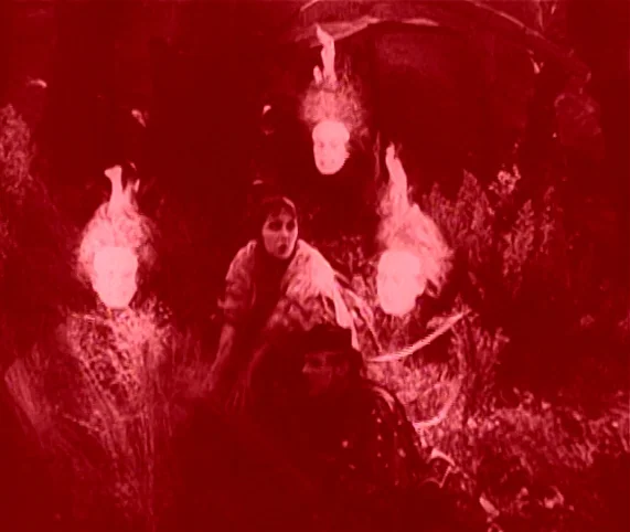 Destiny (1921) movie still: medium — A field filled with dense, dark, overgrown brush at night. Three spectral figures with glowing heads loom over…